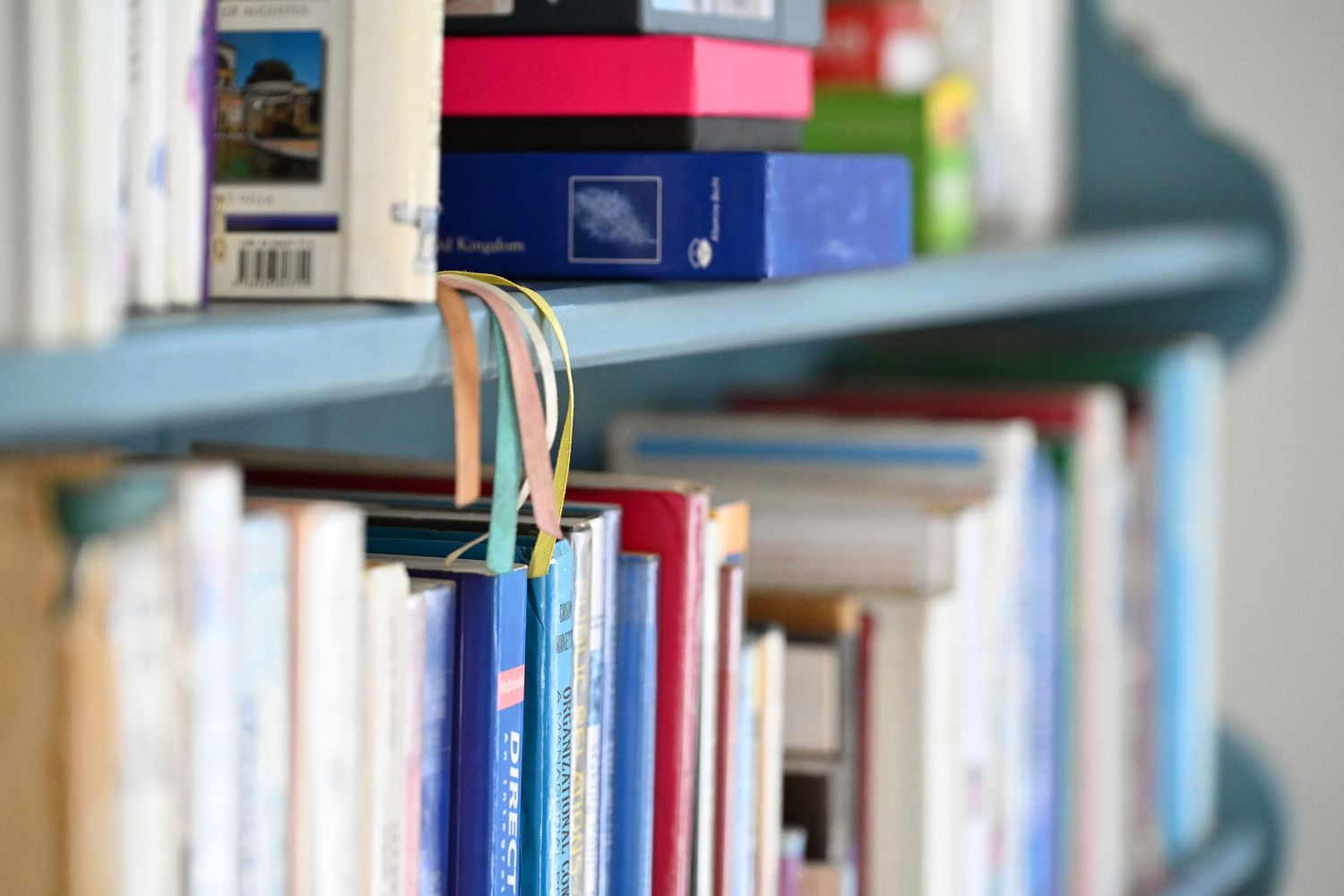 A close detail of a bookshelf, with ribbon bookmarks hanging between books.